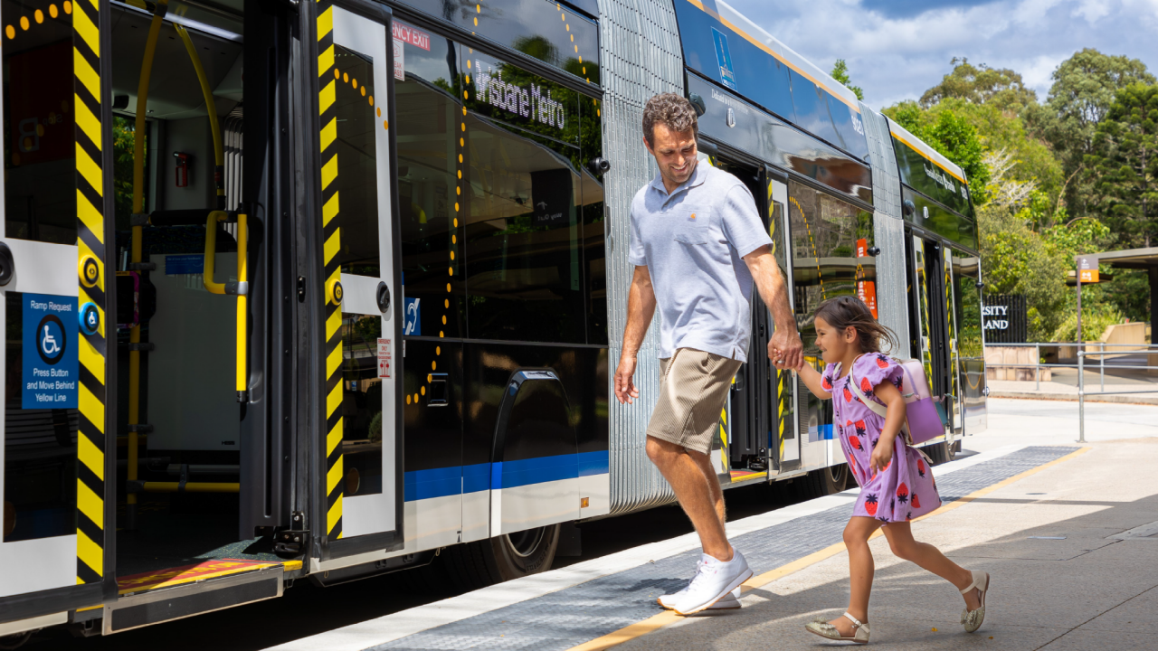 Father and young daughter with backpack boarding a metro.
